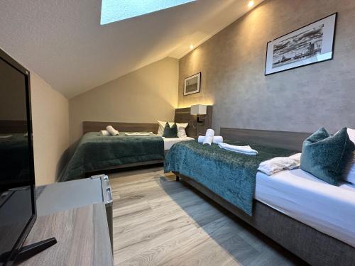 a hotel room with two beds and a flat screen tv at Mertinkus Nordseehotel in Cuxhaven