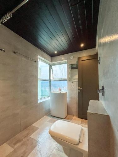 a bathroom with a toilet and a sink and a window at Meraki Hillside Villa in Panchgani