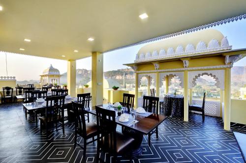 a restaurant with tables and chairs and a view of the city at Padmini Bagh Resort by Inventree, Udaipur in Udaipur