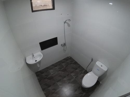 ein weißes Bad mit einem WC und einem Waschbecken in der Unterkunft Omah Nandan Homestay Jogja in Kejayan