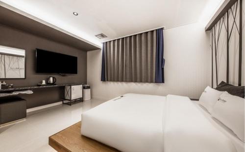 a bedroom with a large white bed and a television at Hotel The Ocean in Mokpo