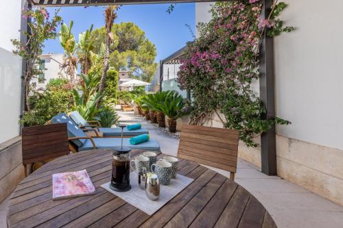 una mesa de madera y sillas en un patio con flores en Apartment La Nau - Fantastic Apartment with hot tub and pool, just steps away from beach, en Puerto Pollensa