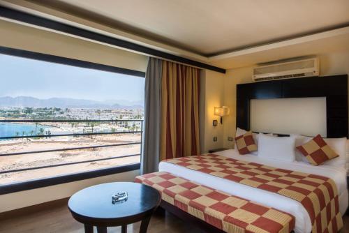 a hotel room with a bed and a large window at Reef Oasis Blue Bay Resort & Spa in Sharm El Sheikh