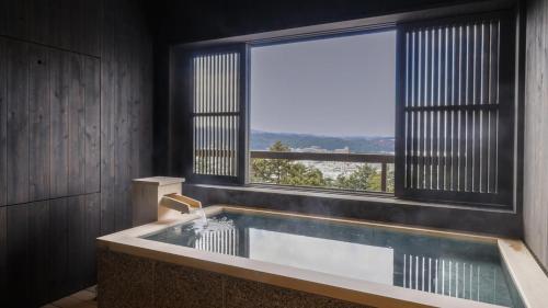 y baño con bañera y ventana grande. en Yoshidaya Sannoukaku, en Kaga