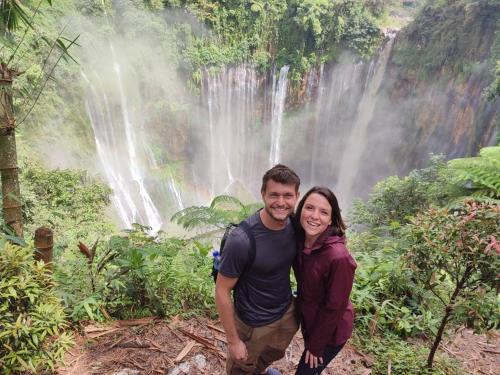 a man and woman standing in front of a waterfall at INNI Homestay in Malang