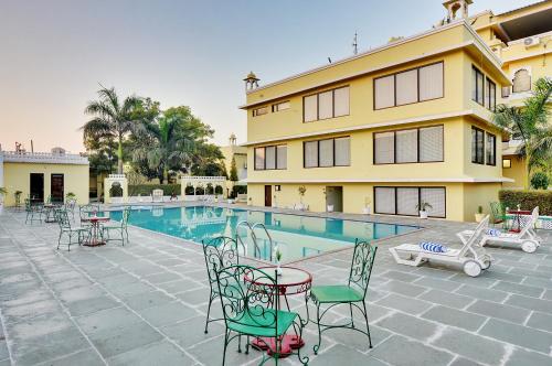 a pool with tables and chairs next to a building at Padmini Bagh Resort by Inventree, Udaipur in Udaipur