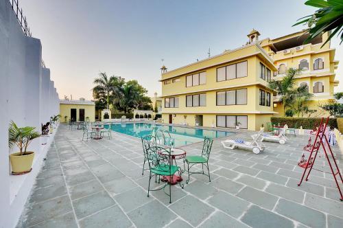 a patio with chairs and a pool and a building at Padmini Bagh Resort by Inventree, Udaipur in Udaipur