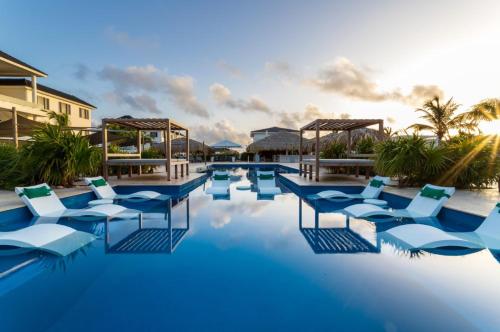 a swimming pool with blue water and lounge chairs at Grand Windsock Bonaire in Kralendijk
