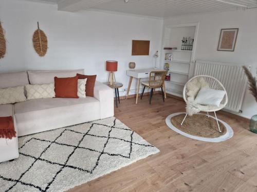a living room with a white couch and a chair at Petite maison chaleureuse avec parking in Leuze-en-Hainaut