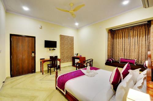 a bedroom with a bed and a table and a desk at Padmini Bagh Resort by Inventree, Udaipur in Udaipur