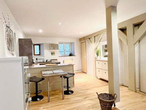 une cuisine avec une table et des tabourets dans une pièce dans l'établissement Gîte de campagne Gaspard, à Macornay