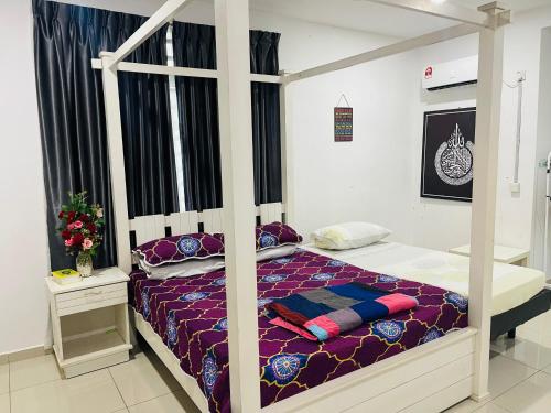 a bedroom with a canopy bed with purple sheets at NO 121 NAZIRIN HOMESTAY TMN DESA MANJUNG in Lumut
