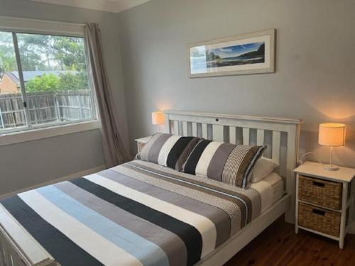 a bedroom with a bed and a window at Watts @ Callala Beach-Pet Friendly in Callala Beach