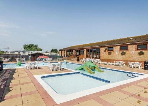 a pool with tables and chairs next to a building at Riverside Caravan Park in Bognor Regis