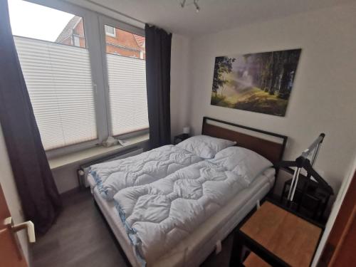 Bett in einem Zimmer mit 2 Fenstern in der Unterkunft Ferienwohnung Lüttje Delftblick in Emden