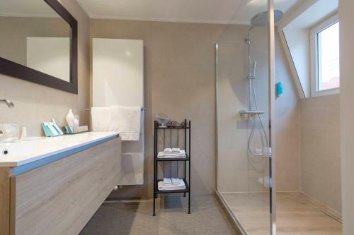 ein Bad mit einem Waschbecken und einer Dusche in der Unterkunft Hotel Lugano in Knokke-Heist