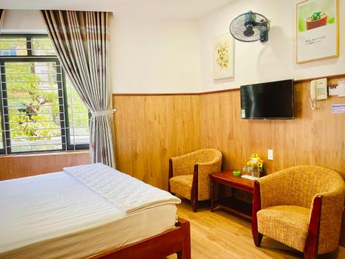 a bedroom with a bed and two chairs and a tv at Nhu Y Hotel in Tuy Hoa