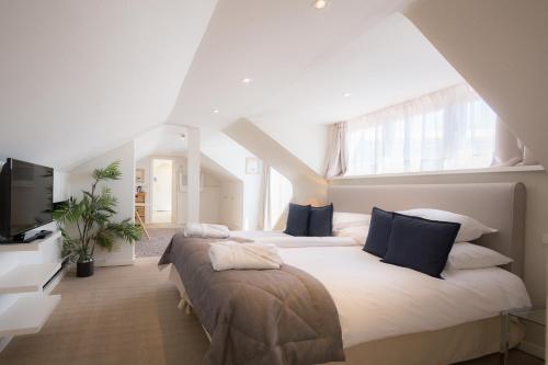 a bedroom with two beds and a flat screen tv at Hotel Lugano in Knokke-Heist