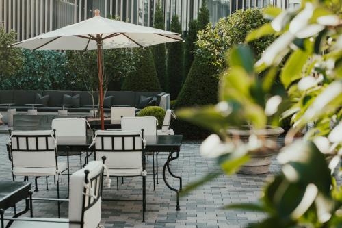 a patio with tables and chairs and an umbrella at Hotel Pacai, Vilnius, a Member of Design Hotels in Vilnius
