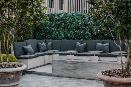 a couch with pillows sitting in a courtyard with trees at Hotel Pacai, Vilnius, a Member of Design Hotels in Vilnius