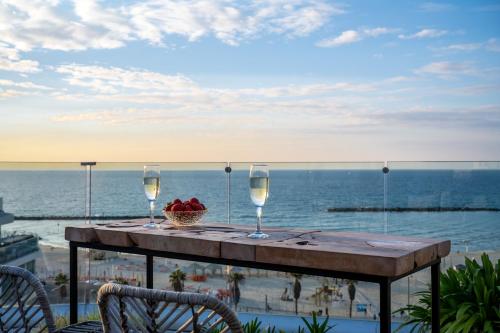 uma mesa com dois copos de vinho e uma cesta de frutas em Maxim Design Hotel 3 Star Superior em Tel Aviv