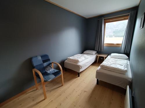 a room with two beds and a chair and a window at Fossanmoen in Forsand