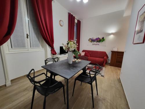een woonkamer met een tafel en stoelen en een rode bank bij La Câza a Zêna in Genua
