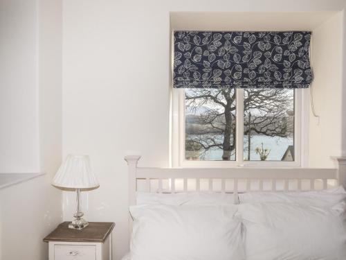 a bedroom with a bed and a window with a curtain at Cae Gallt in Menai Bridge