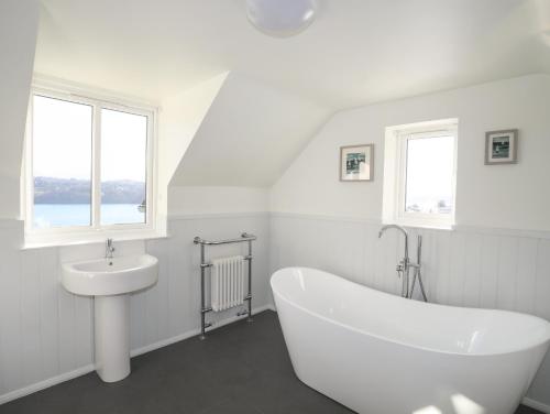 a white bathroom with a tub and a sink at Cae Gallt in Menai Bridge