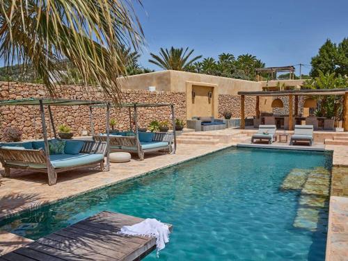 a swimming pool with chairs and a house at Kasbah Darshan in Cala Vadella