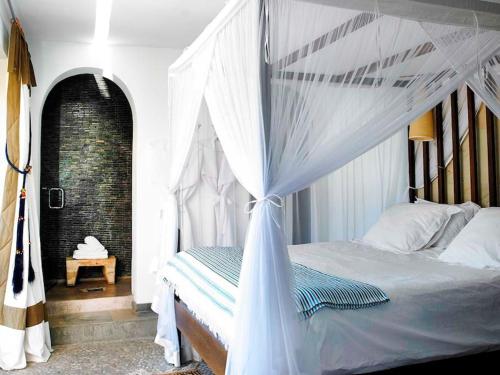 a bedroom with a white bed with a canopy at Kasbah Darshan in Cala Vadella