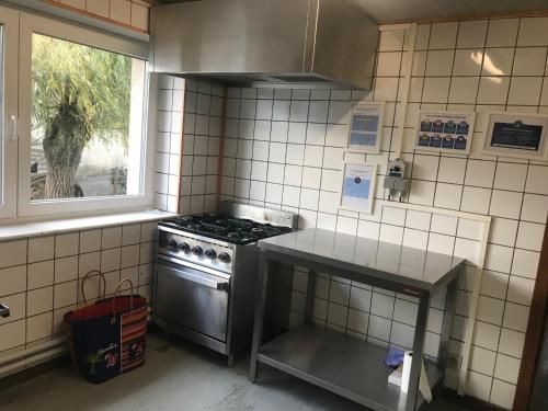 eine Küche mit einem Herd und einem Fenster in der Unterkunft Centre Louis Delobbe in Olloy-sur-Viroin