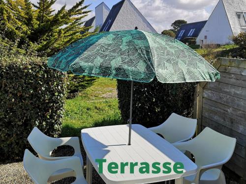 - une table et des chaises avec un parasol dans l'établissement Maisonnette T2 Bord de mer Guidel Plage, à Guidel