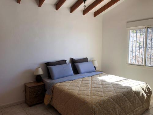 a bedroom with a bed with blue pillows and a window at Panoramavilla Lofio Spain in Cómpeta
