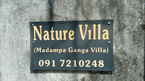 a sign on the side of a stone wall at Madampa Ganga Villa. in Ambalangoda