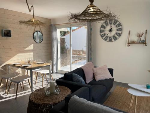 un salon avec un canapé et une horloge au mur dans l'établissement Maison au calme près des plages, à Le Poiroux