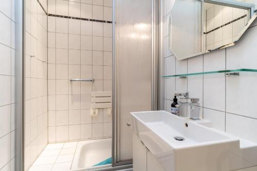 biała łazienka z umywalką i prysznicem w obiekcie Ferienwohnung Finkwarder w mieście Westerdeichstrich