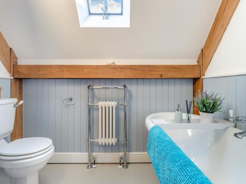 a bathroom with a tub and a toilet and a sink at Chestnut Cottage in Leighton