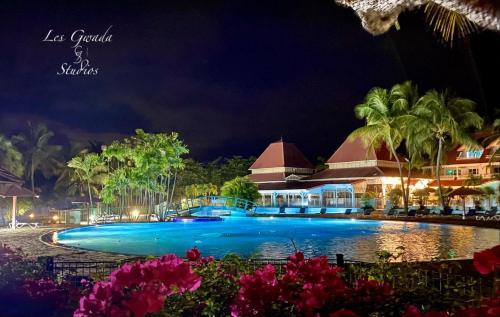 una piscina in un resort di notte di Vue Exclusive Mer et Volcan, Village Vacances avec Plage et Piscine, Les Gwadastudios a Sainte-Anne