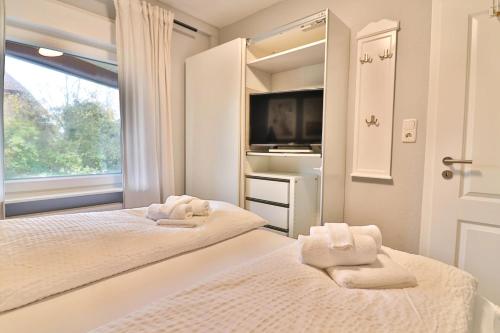 a bedroom with two beds and a tv and a window at Langeooger Viermaster - Blaues Segel in Langeoog
