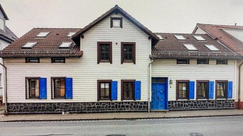 a white house with blue shutters on a street at Ferienwohnung sentio-comfortable Saalfeld in Saalfeld