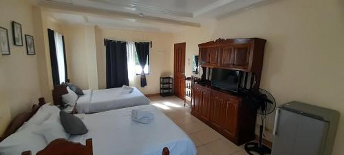 a hotel room with two beds and a television at CORALYN'S PLACE Family of 5 in Boracay
