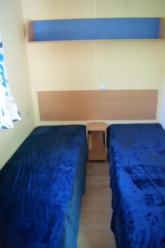 - 2 lits dans une chambre avec des draps bleus dans l'établissement Camping le Chambron, à Condorcet