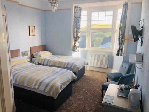 a bedroom with two beds and a desk and a chair at Varley House in Ilfracombe