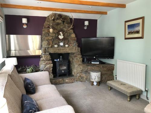 a living room with a stone fireplace and a television at The Cottage Cox Hill Chacewater in Truro