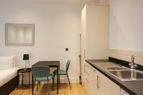 Swindon Apartments by Charles Hope في سويندون: مطبخ مع مغسلة وطاولة وكراسي