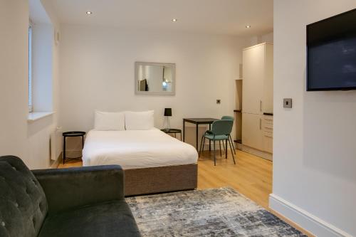 a bedroom with a bed and a couch and a tv at Swindon Apartments by Charles Hope in Swindon