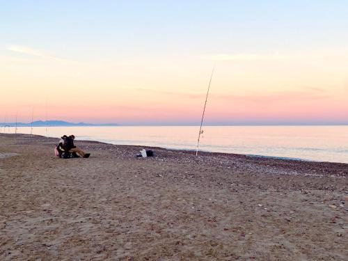 a person sitting on a beach with a fishing pole at Lowenva beach apartment in Canet de Berenguer