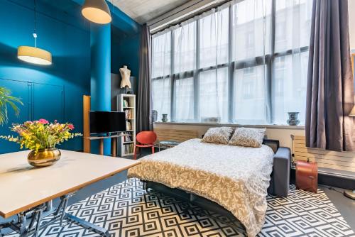 - une chambre avec des murs bleus, un lit et un bureau dans l'établissement Mon loft, à Asnières-sur-Seine