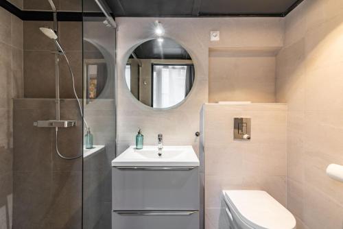 ein Badezimmer mit einem Waschbecken, einem WC und einem Spiegel in der Unterkunft Mon loft in Asnières-sur-Seine